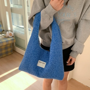 Détail du sac cabas en peluche bleue avec étiquette en tissu blanc et doublure à carreaux