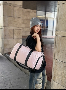 Pink travel bag shown on a model featuring dry-wet separation and reinforced black straps