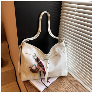 Detail of white PU leather tote bag with silver buckles and a cute plush bear charm
