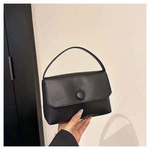 Detail of black faux leather handbag with lychee texture and round buckle closure