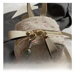 Detail of tweed fabric texture and bright gold hardware on a mini backpack with charm