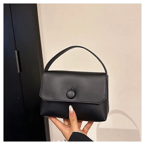 Detailed view of a black minimalist leather handbag with textured pebble grain finish