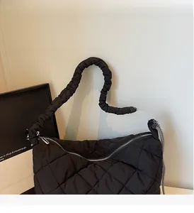 Detail of black quilted tote bag showing padded texture and striped side ribbon