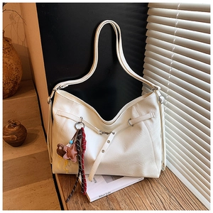 Close-up of white PU leather hobo tote bag with crossbody straps and a cute teddy bear charm