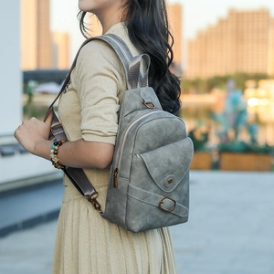 Detalle de bolso bandolera gris con hebilla metálica en modelo en entorno urbano exterior