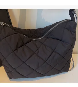 Detail of black quilted puffer tote featuring large diamond pattern and woven strap