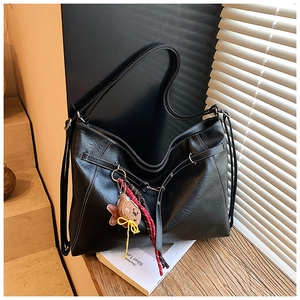 Detail of black tote bag with white contrast stitching and cute teddy bear charm