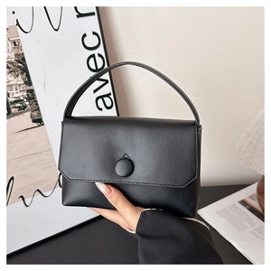 Close-up of black lychee grain leather handbag with minimalist circular buckle and top handle