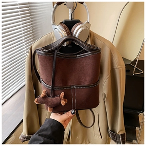 Detail view of brown bucket bag with contrast stitching and decorative dog charm