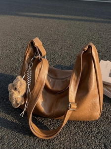 Brown vintage faux leather tote bag with wide strap and cute bear charm outdoor view