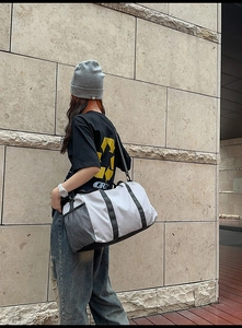 Close-up of grey travel duffel bag with mesh side pocket and adjustable shoulder strap