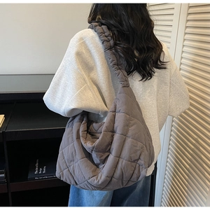 Detail of grey quilted tote bag with diamond stitching and ruffled shoulder strap