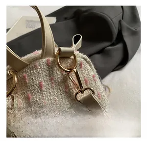 Close-up of golden metal hooks on white tweed backpack with pink fiber details