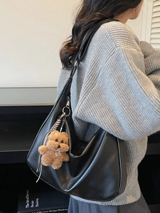 Stylish black leather tote bag with a cute brown plush bear charm for daily use