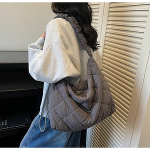 Close-up of hobo bag with quilted rhombus pattern and ruffled shoulder strap detail