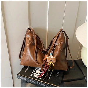 Detailed view of brown PU leather tote bag with pleat design and cute bear pendant