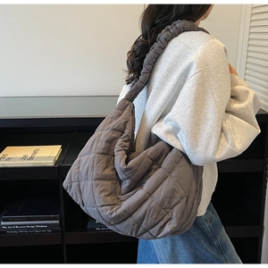 Detail of grey quilted tote bag featuring a trendy ruffled scrunchie style shoulder strap