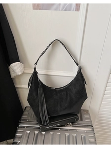 Detail view of black hobo bag with fringe pendant and geometric patterned shoulder strap