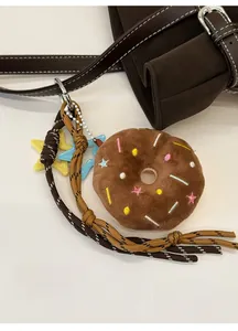 Detail of doughnut plush charm with colorful embroidery on a dark brown shoulder bag