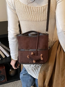 Fashionable brown frosted bucket bag with contrast stitching and plush puppy pendant accessory