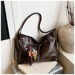 Detail of dark brown faux leather hobo bag with teddy bear charm on vintage decor