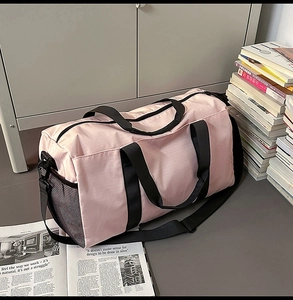 Close-up of pink travel duffel bag with black mesh side pocket and adjustable shoulder strap