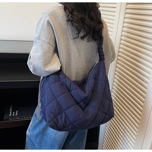 Detail of navy blue quilted puffer tote featuring a ruched strap and high-capacity moon shape