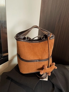 Brown suede bucket bag with leather handles and cute teddy dog charm in retro style