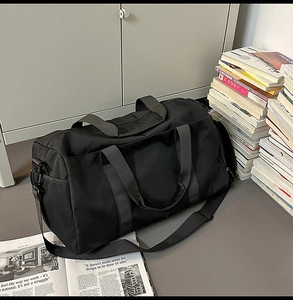 Close-up of black travel bag with side mesh pocket and adjustable shoulder strap