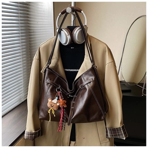 Detail of dark brown leather tote bag with star and bear pendant in a fashion setting