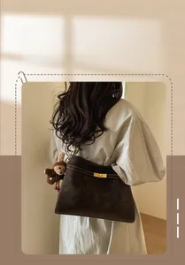 Détail du sac sous l'aisselle en cuir mat marron foncé avec fermoir doré et lapin