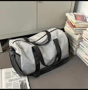 Detailed close-up of grey travel bag featuring mesh side pocket and durable nylon texture
