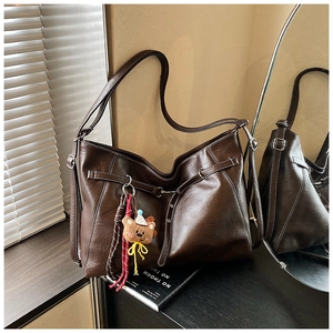 Detail of dark brown PU leather tote bag with white contrast stitching and bear charm