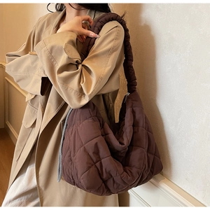 Detail of dark brown quilted tote bag with unique ruched shoulder strap on model