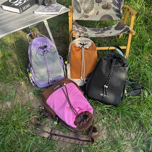 Zaini con coulisse in vari colori sull'erba con attrezzatura da campeggio