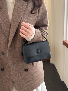 Minimalist black leather handbag with round buckle shown in a lifestyle commuter outfit