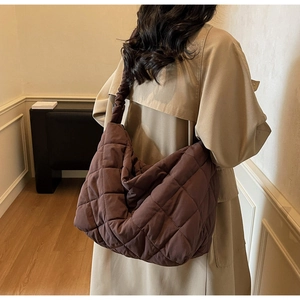 Rear view of model wearing a large brown quilted tote bag with soft pleated shoulder straps