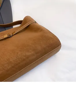 Detail of caramel suede tote bag with golden twist-lock and contrast stitching