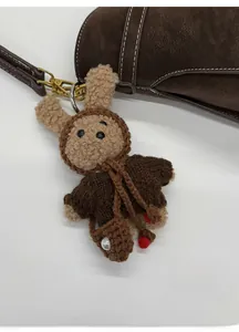 Détail d'un porte-clé lapin en peluche fait main avec fermoir doré sur sac en cuir