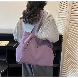 Purple large capacity nylon tote bag with drawstring side pocket shown on shoulder