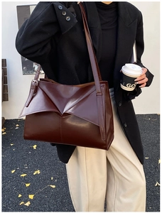 Vista street style di una borsa tote geometrica bordeaux indossata a spalla da donna