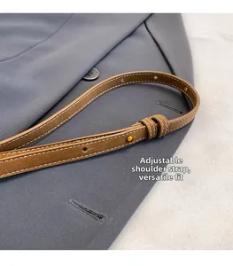 Detail of adjustable brown leather strap with contrast stitching and gold buckle