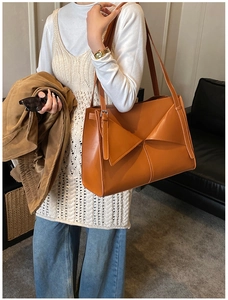 Foto lifestyle di una borsa tote in pelle arancione con patta triangolare e tracolla