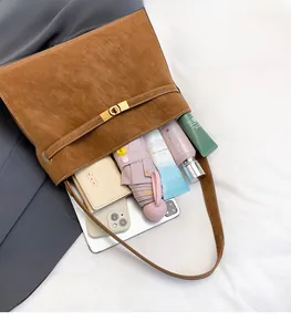 Internal storage view of brown suede tote bag showing tablet, phone, and makeup essentials