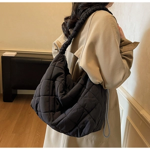 Detail of black quilted hobo bag with unique ruched shoulder strap and puffy design
