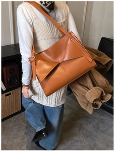 Dettaglio macro della borsa tote marrone con piega geometrica e trama in pelle opaca fine