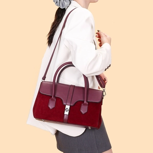Detail view of burgundy tote bag with suede paneling and elegant metal twist lock
