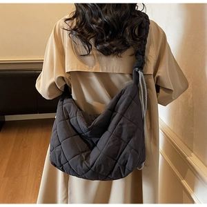 Rear view of a model wearing a large black quilted tote bag with stripe drawstring details