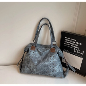 Gros plan du sac fourre-tout vintage avec rivets argentés et poignées en cuir contrasté