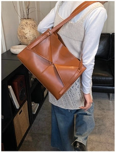 Dettaglio di una borsa tote grande in pelle opaca marrone con struttura geometrica unica
